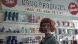 A teenage girl with red hair stands in a drug store.