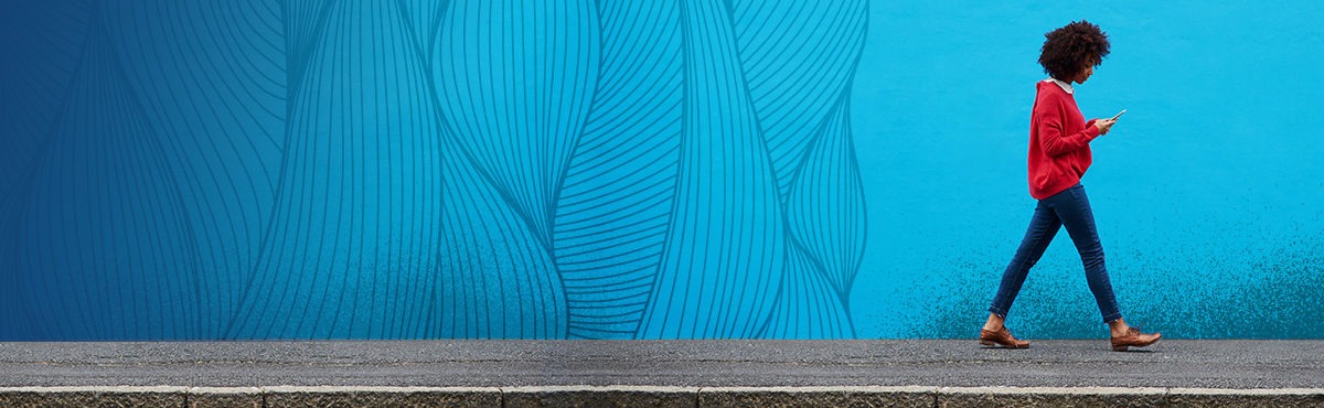 A gen z woman walks on a sidewalk in front of a bright blue wall with an organic strand texture. The woman and texture represent the relationship of buyer needs and expectations and a seller's capacity for success through honoring the customer.